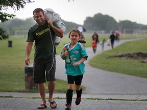 Scot Fryer and his daughter Mikayla run as rain pours down as soccer games were cancelled due to lightning at the Ford Test Track Windsor, Ontario on July 29, 2014.   (JASON KRYK/The Windsor Star)