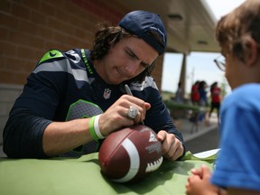 LaSalle native Luke Willson, left, of the Seattle Seahwks signs a football for Nash Jones, 7, at the Vollmer Centre, Saturday, July 5, 2014. (DAX MELMER/The Windsor Star)