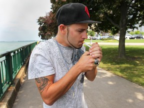 James Maisonneuve, 25, smokes a cigarette on Thursday, July 31, 2014, along the downtown Windsor, ON. waterfront. (DAN JANISSE/The Windsor Star)