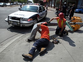 City of Windsor traffic department workers prepare to remove a crushed traffic light after a 18-wheeler made a hard right turn fron Ouellette Avenue onto Wyandotte Street West August 6, 2014. (NICK BRANCACCIO/The Windsor Star)