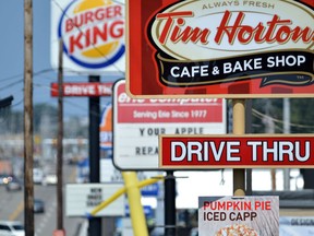 Signs for a Tim Hortons restaurant, foreground, and a Burger King restaurant are displayed along Peach Street Tuesday, Aug. 26, 2014, in Erie, Penn. Burger King struck an $11 billion deal to buy Tim Hortons that would create the world's third largest fast-food company and could make the Canadian coffee-and-doughnut chain more of a household name around the world. (AP Photo/Erie Times-News, Christopher Millette)