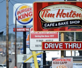 Signs for a Tim Hortons restaurant, foreground, and a Burger King restaurant are displayed along Peach Street Tuesday, Aug. 26, 2014, in Erie, Penn. Burger King struck an $11 billion deal to buy Tim Hortons that would create the world's third largest fast-food company and could make the Canadian coffee-and-doughnut chain more of a household name around the world. (AP Photo/Erie Times-News, Christopher Millette)