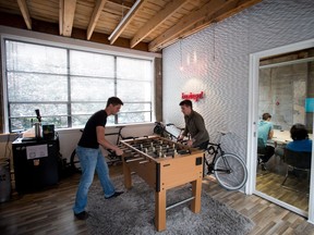 Hubert Florin, left, a senior designer, and Ryan Betts, direct of user experience, play foosball during a break as others hold a meeting at Bazinga! in Vancouver, B.C., on Wednesday August 13, 2014. The company offers a cloud-based platform for online interaction between residents in condo buildings and property management and developers. THE CANADIAN PRESS/Darryl Dyck