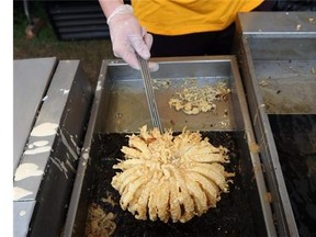 A  blooming onion from a deep fryer at the Washington County Fair on Thursday, Aug. 21, 2014, in Greenwich, N.Y. The creators of fair concoctions say they work all year to outdo themselves and the other vendors vying for the attention of an ever more expectant public. (AP Photo/Mike Groll)