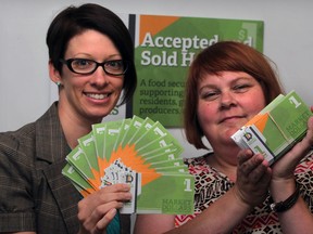 Laura Tucker, left, community engagement co-ordinator for Pathway To Potential and Michele Legere, co-ordinator Food Matters Windsor Essex County, hold Market Dollars which are available for agencies and businesses to distribute to needy families and can be used to purchase food at Downtown and Ford City Farmers' Markets, Monday August 18, 2014.  (NICK BRANCACCIO/The Windsor Star)