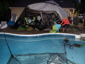 Vera Drude of 3080 California Avenue tries to pick up the pieces after a strong storm raced through neighbourhoods in South Windsor Tuesday August 19, 2014. (NICK BRANCACCIO/The Windsor Star)