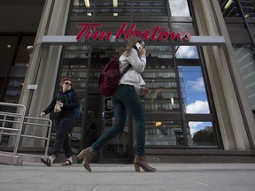 Pedestrians walk past a Tim Hortons Inc. restaurant in Toronto, Ontario, Canada, on Tuesday, Sept. 17, 2013. Tim Hortons Inc. Chief Executive Officer Marc Caira said Canadaís largest coffee and doughnuts chain must succeed in the U.S. as competition brings slower growth at home. Photographer: Brent Lewin/Bloomberg