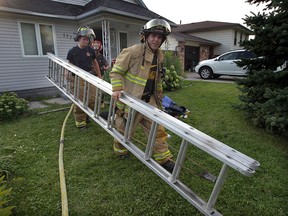 Tecumseh firefighters John White and Nick Jovanovic, left, remove a ladder following a house fire at 1779 Lesperance Road Friday August 22, 2014. Two occupants were displaced and the fire cause $40,000 damage. (NICK BRANCACCIO/The Windsor Star)