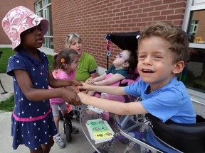 Student Amanesi, left, holds the hands of Andrzej, right, during a sing-along with pre-school teacher Stephanie Letkeman at John McGivney Children's Centre, August 27, 2014. Joining the fun were students Mackenzie, behind left, and Madison, sitting in stroller. (NICK BRANCACCIO/The Windsor Star)