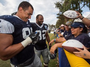 Windsor's Tyrone Crawford, left, and teammate Jeremy Mincey of the Dallas Cowboys sign autographs at the end of practice in Oxnard, Calif. (AP Photo/Ringo H.W. Chiu)