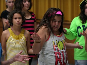 va Toutant, left, Olivia D'Alfonso and Danica Grech, behind right, express themselves with other students during Super Heroes rehearsal at The Space youth drama camp Thursday July 31, 2014. Later, students were treated to a cool down courtesy of Windsor Fire Service Engine 5 who supplied a refreshing sprinkler Thursday July 31, 2014.  Students at the camp are taught dance, music and choreography and perform a play every week.  -- (NICK BRANCACCIO/The Windsor Star)