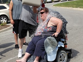 Renee Ganley gets a hand from John Broughton as she joins staff and other residents of the Village of Aspen Lake as they take the ice bucket challenge in front of the residence in Windsor on Monday, August 25, 2014. The group hoped to raise 500 dollars for ALS.              (Tyler Brownbridge/The Windsor Star)