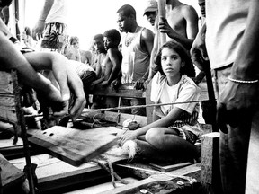 In this 1994 photo made by William Castellanos, a young girl looks solemnly out of a wooden raft. Thousands of Cubans were building makeshift rafts and throwing them into the sea after then-President Fidel Castro said anyone who wanted to leave could flee. Castellanos grabbed his old F-3 Nikon camera and began taking photos. Castellanos now lives in Miami and is working on an exhibit of his images. (AP/William Castellanos)