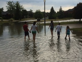 Area residents walk down a flooded section of Christina Crescent in Windsor following heavy rainfall last week. The city is offering another day of curbside collection for flood-damaged trash. (Jason Kryk/The Windsor Star)