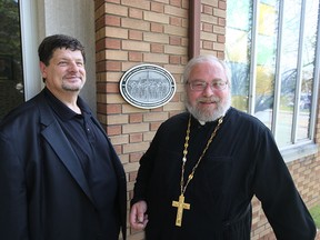Fred Kushnir and Father Roman Kocur are shown with a  A  plaque commemorating the internment of 8,579 people from 1914 to 1920 at the Ukrainian Orthodox Cathedral Of St Vladimir on Tecumseh Road east in Windsor, Ontario on August 22, 2014.  100 locations across Canada held dedication ceremonies for the plaque. (JASON KRYK/The Windsor Star)