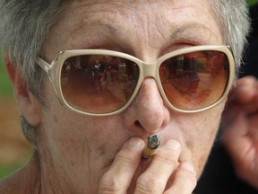 A woman smokes marijuana near Windsor, ON. city hall square on Tuesday, August 12, 2014. He was part of a group of supporters awaiting the arrival in Canada of marijuana activist Marc Emery. (DAN JANISSE/The Windsor Star)