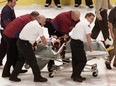 In this March 8, 2004, file photo, Colorado Avalanche NHL hockey player Steve Moore is taken off the ice by medical staff after he was hit by Vancouver Canucks' Todd Bertuzzi during the third period of NHL action in Vancouver, British Columbia. A settlement has been reached in Moore's lawsuit against Bertuzzi for his career-ending hit during an NHL game 10 years ago. (The Canadian Presss, Chuck Stoody, File)