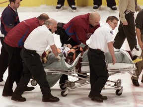 In this March 8, 2004, file photo, Colorado Avalanche NHL hockey player Steve Moore is taken off the ice by medical staff after he was hit by Vancouver Canucks' Todd Bertuzzi during the third period of NHL action in Vancouver, British Columbia. A settlement has been reached in Moore's lawsuit against Bertuzzi for his career-ending hit during an NHL game 10 years ago. (The Canadian Presss, Chuck Stoody, File)