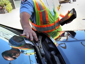 WINDSOR, ONTARIO- AUGUST 14, 2014 - A bylaw enforcement officer tickets a car in downtown Windsor, ON. on Thursday, August 14, 2014. (DAN JANISSE/The Windsor Star) (For story by Carolyn Thompson)