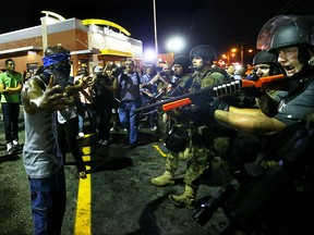 Police officers move in to arrest protesters as they push and clear crowds out of the West Florissant Avenue area in Ferguson, Mo. early Wednesday, Aug. 20, 2014. On Aug. 9, 2014, a white police officer fatally shot Michael Brown, an unarmed black 18-year old, in the St. Louis suburb. (AP Photo/Atlanta Journal-Constitution, Curtis Compton)