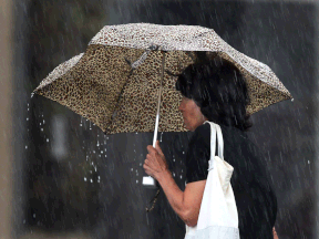 A woman in downtown Windsor attempts to shield herself from heavy rain with an umbrella on Aug. 11, 2014. (Dan Janisse / The Windsor Star)