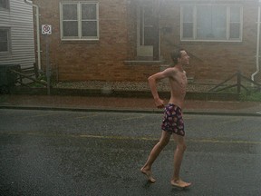 Jacob Bahry, 16, runs in the pouring rain in his under shorts outside a Tim Hortons in Amherstburg, Ont., Monday, August 11, 2014.   (DAX MELMER/The Windsor Star)