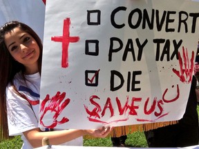 Mary Ashoor holds up a sign at the rally at City Hall Sunday, August 17, 2014, in support of thousands of Christians being forced to leave their homes in Iraq. (JOEL BOYCE/The Windsor Star)