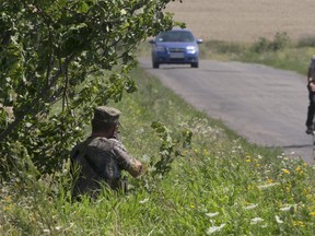 A pro-Russian rebel stands on guard near the village of Hrabove, area of the Malaysia Airlines Flight 17 plane crash, Donetsk region, eastern Ukraine Friday, Aug. 1, 2014. With the sound of artillery blasts at a distance, dozens of international investigators arrived Friday at the eastern Ukraine site where Malaysia Airlines Flight 17 crashed and began a painstaking search for the remains of as many as 80 victims. (AP Photo/Dmitry Lovetsky)