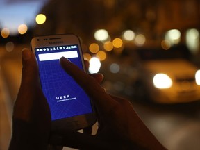 In this photo illustration, a woman uses the Uber app on a smartphone. UberX is already available in several North American cities including Los Angeles, Chicago, New York, Washington, D.C., Houston, Miami and Mexico City.