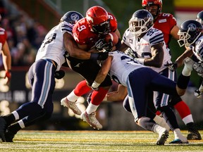 Toronto Argonauts' Shane Horton, left, and Nick Rosamonda, right, tackle Calgary Stampeders' Jon Cornish, during first half CFL football action in Calgary, Alta., Saturday, Sept. 13, 2014. THE CANADIAN PRESS/Jeff McIntosh