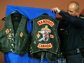 An OPP officer places biker vests seized in raids on display prior to a news conference in London, Ont., Monday April 10, 2006. Five people have been arrested and charged with first-degree murder in the gangland-style shooting of eight men who were associated with or full-fledged members of the notorious Bandidos motorcycle gang, police said Monday. (CP PHOTO/Adrian Wyld)