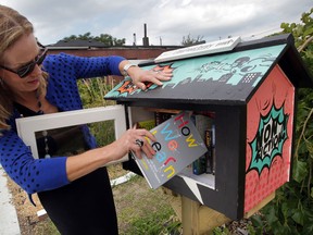 Janice Forsythe of Windsor Rotary (1918) shows how easy it is to use Little Free Library at the Ford City Community Garden location Thursday September 18, 2014. (NICK BRANCACCIO/The Windsor Star)