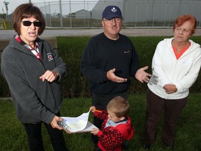 Gloria and Ed Burling, left, and Eleanor Dame, right, all residents of North Rear Road, have concerns over what they describe as "an eyesore" Friday September 19, 2014. Two majiuana processing facilities on North Rear Road have been built, complete with security cameras and layers of barbed wire fencing. Burling's grandson, Dustin, 2, checks out his grandmother's notes. (NICK BRANCACCIO/The Windsor Star)