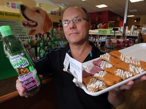 For Your Fur Kids owner Victor Pundzius displays peanut butter and jam and cheese and bacon dog bones in one hand and a pet oral care additive in other, Monday September 22, 2014. (NICK BRANCACCIO/The Windsor Star)