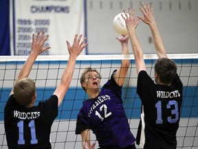 Kingsville's Zachary Booth, centre, tries to spike the volleyball past Villanova's Jon Grebe, left, and Thomas Swiateshik during senior boys volleyball action at Villanova Tuesday. (JASON KRYK/ The Windsor Star)