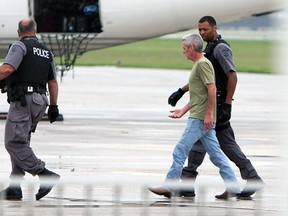 A man is escorted off a plane after the flight was greeted by police officers on the ground in Windsor on Tuesday, September 2, 2014. The flight crew requested police after a pair of passengers became unruly on the flight from Calgary.               (Tyler Brownbridge/The Windsor Star)