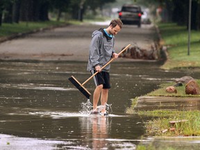 Adam Quinlan tries to locate a sewer drain near his South Windsor home at California and Norfolk after heavy rains hit the area on Wed. Sept. 10, 2014. (DAN JANISSE/The Windsor Star)