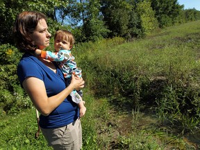 Carey Kern holds her son David as she stares out across the neighbours field in Woodslee on Tuesday, September 9, 2014. Kern feels the Country Village nursing home is responsible for the flooding that is happening on her property.                     (TYLER BROWNBRIDGE/The Windsor Star)