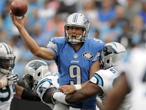 Lions QB Matthew Stafford, centre, is hit as he throws a pass against the Carolina Panthers during the second half in Charlotte, N.C., Sunday, Sept. 14, 2014. (AP Photo/Mike McCarn)