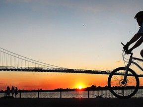 A cyclist cruises near the Ambassador Bridge on Wednesday, Sept. 3, 2014, as the sun set on warm summer day. (DAN JANISSE/The Windsor Star)
