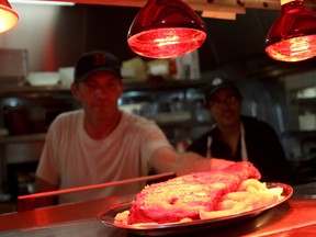A Tunnel Bar-B-Q cook places a slab of ribs on the counter inside the restaurant on Park Street East, Monday, Sept. 1, 2014. TBQ closed its doors to make way for a new University of Windsor expansion. (RICK DAWES/The Windsor Star)