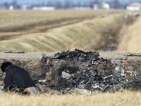 A police officer examines vehicle parts in a charred ditch — the scene of a fatal car crash near Tilbury on Feb. 5, 2012. (Dax Melmer / The Windsor Star)