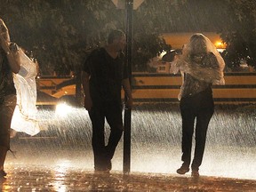 A trio leaves the Shores of Erie International Wine Festival on Friday, Sept. 5, 2014, during a heavy downpour that shut down the event for the night. (DAN JANISSE/The Windsor Star)