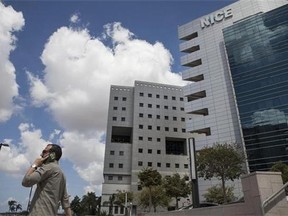 In this photo taken Sunday, Sept. 14, 2014 an Israeli man speaks on the phone next to the NICE Systems Ltd buildings in the city of Raanana, Israel. Businesses and governments around the world are increasingly turning to voice biometrics, or voiceprints, to replace passwords and fight fraud. Wells Fargo, the San Francisco-based bank, uses voices screening technology, also known as voice biometric blacklists, provided by NICE. (AP Photo/Dan Balilty)