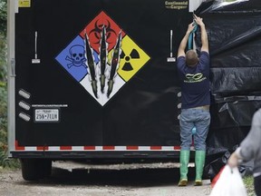 A hazmat worker puts up a plastic sheet before starting to clean the apartment building of a hospital worker, Sunday, Oct. 12, 2014, in Dallas. Top federal health officials said that the Ebola diagnosis in a health care worker who treated Thomas Eric Duncan at a Texas hospital clearly indicates a breach in safety protocol. (AP Photo/LM Otero)