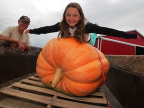 Sylvie Lachance rides a huge pumpkin grown by her uncle Roch Ethier and her grandfather Clement Lachance, left.  The effort to grow large pumpkins was to honour Roch's son, Daniel, who died of cancer in June 2013.  (NICK BRANCACCIO/The Windsor Star)  See story.