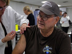 Richard Cowley, right, receives his Vaxigrip flu vaccine from RN Karen Fields at Windsor-Essex Health Unit on Ouellette Avenue Tuesday October 21, 2014.  10 nurses stations were set up to handle a lineup of area residents who were patiently waiting at the door when the clinic opened at 3 p.m.  (NICK BRANCACCIO/The Windsor Star)