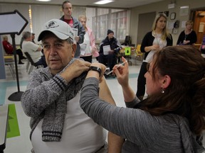 Sid Hurst, left, receives his Vaxigrip flu vaccine from RN Jennifer Johnston, right, at Windsor-Essex Health Unit on Ouellette Avenue Tuesday October 21, 2014.  10 nurses stations were set up to handle a lineup of area residents who were patiently waiting at the door when the clinic opened at 3 p.m.  (NICK BRANCACCIO/The Windsor Star)