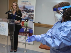 Karen Riddell, right, director of professional practice and operations at Windsor Regional Hospital, displays the personal protective equipment hospital workers use when a patient is suspected of having a communicable disease during a press conference at Windsor Regional Hospital - Ouellette Campus outlining the hospital's preparedness for Ebola, Monday, Oct. 20, 2014.  Erik Vitale, left, manager of infection prevention and control explains how to properly put on the equipment.  (DAX MELMER/The Windsor Star)
