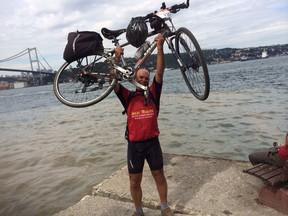 Lloyd Strong raises his bike after completing a cycling expedition from Shanghai to Istanbul. It completed his quest to cycle around the world in a linear fashion. (Courtesy of Lloyd Strong)